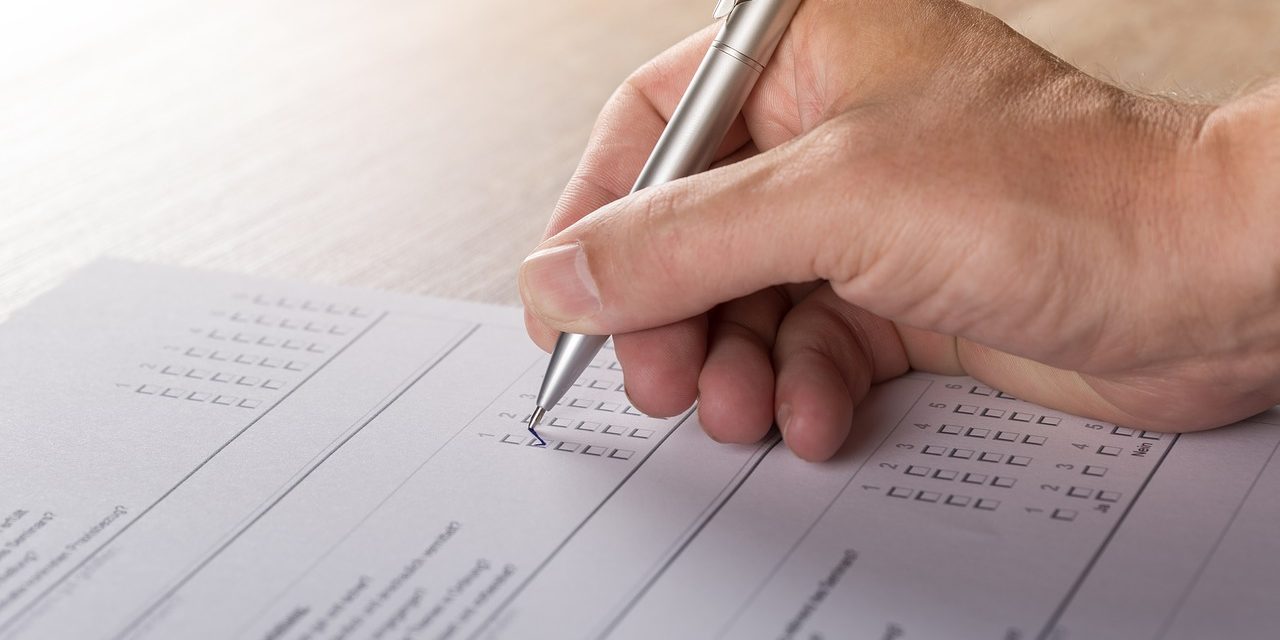 Picture of person completing a survey. Only hand is visible.